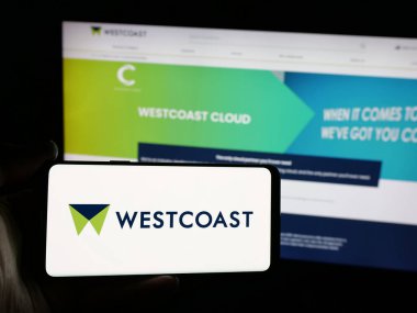 Stuttgart, Almanya - 03-04-2025: İngiliz bilişim şirketi Westcoast Limited 'in logosuna sahip akıllı telefon sahibi kişi web sitesinin önünde ekranda. Telefon ekranına odaklan.