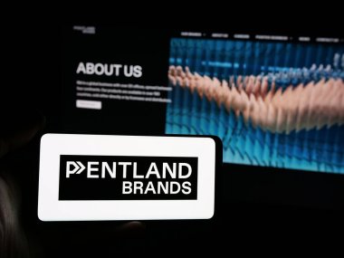 Stuttgart, Almanya - 03-04-2025: İngiliz perakende şirketi Pentland Group plc 'nin logosuna sahip akıllı telefon sahibi kişi iş sitesinin önünde ekranda. Telefon ekranına odaklan.