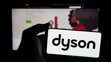 Stuttgart, Almanya - 03-04-2025: Ev aletleri şirketi Dyson Limited 'in logosuna sahip cep telefonu sahibi kişi iş sayfasının önünde ekranda. Telefon ekranına odaklan.