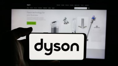 Stuttgart, Almanya - 03-04-2025: Ev aletleri şirketi Dyson Limited 'in logosuyla cep telefonu sahibi kişi iş sayfasının önünde ekranda. Telefon ekranına odaklan.