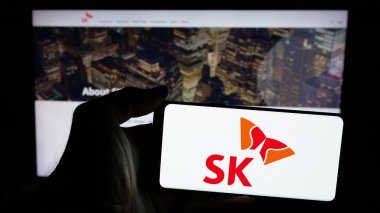 Stuttgart, Almanya - 03-13-2025: Güney Koreli şirket SK Group 'un logosunun bulunduğu cep telefonu sahibi kişi iş sayfasının önünde ekranda. Telefon ekranına odaklan.