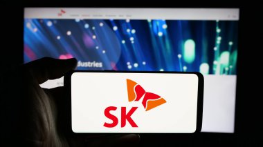 Stuttgart, Almanya - 03-13-2025: Güney Koreli şirket SK Group 'un logosuyla cep telefonu sahibi kişi iş sayfasının önünde ekranda. Telefon ekranına odaklan.