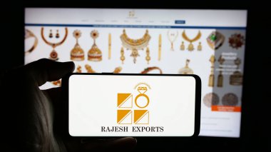 Stuttgart, Almanya - 03-13-2025: Üzerinde Hint altın şirketi Rajesh Exports Limited 'in logosu olan cep telefonu sahibi kişi iş sayfasının önünde ekranda. Telefon ekranına odaklan.