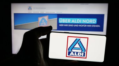 Stuttgart, Almanya - 03-13-2025: Alman ALDI Nord Deutschland Stiftung Co. KG logosunun bulunduğu cep telefonu sahibi kişi iş sayfasının önünde ekranda. Telefon ekranına odaklan.