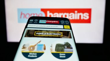 Stuttgart, Almanya - 03-13-2025: İngiliz şirketi T.J. Morris Limited 'in logosunun yer aldığı cep telefonu (Home Bargains) iş sitesinin önünde ekranda. Telefon ekranının sol üst kısmına odaklan.