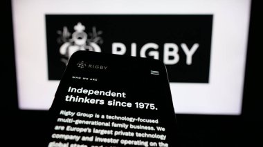 Stuttgart, Almanya - 03-13-2025: İngiliz firması Rigby Group plc 'in logosunun yer aldığı cep telefonu iş sitesinin önünde ekranda. Telefon ekranının sol üst kısmına odaklan.