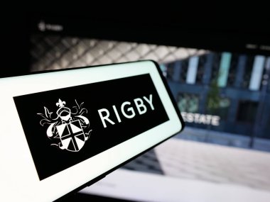 Stuttgart, Almanya - 03-13-2025: İngiliz firması Rigby Group plc 'in logosuna sahip akıllı telefon iş sitesinin önünde ekranda. Telefon ekranının merkez soluna odaklan.