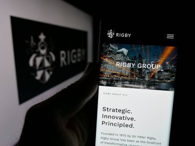 Stuttgart, Almanya - 03-13-2025: İngiliz firması Rigby Group plc 'in web sayfası olan cep telefonu logosu önünde ekranda. Telefon ekranının merkezine odaklan.