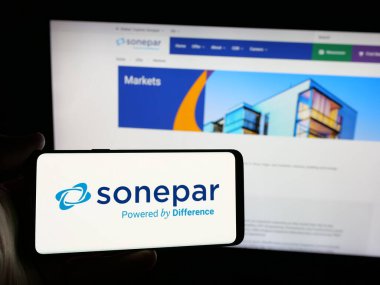 Stuttgart, Almanya - 03-06-2025: Fransız elektronik toptan satış şirketi Sonepar S.A. 'nın logosuna sahip akıllı telefon sahibi kişi iş sitesinin önünde ekranda. Telefon ekranına odaklan.