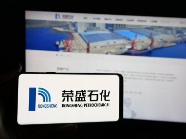 Stuttgart, Almanya - 03-06-2025: Çinli şirket Rongsheng Petrochemical Co. Ltd. (CNRSPC) 'nin logosuna sahip kişi iş sitesinin önünde ekranda görülüyor. Telefon ekranına odaklan.