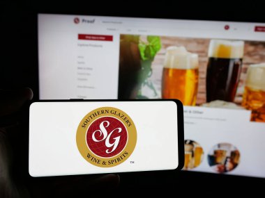 Stuttgart, Almanya - 03-06-2025: ABD 'li şirket Southern Glazer' s Wine and Spirits LLLC 'nin logosunu taşıyan kişi iş sitesinin önünde ekranda. Telefon ekranına odaklan.