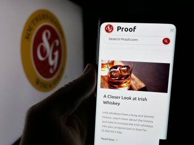 Stuttgart, Almanya - 03-06-2025: Logo önünde ekranda, üzerinde Southern Glazer 's Wine and Spirits LLLC logosu bulunan kişi. Telefon ekranının merkezine odaklan.