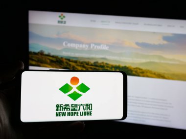 Stuttgart, Almanya - 03-06-2025: Çinli gıda şirketi Yeni Umut Liuhe Co. Ltd. 'nin logosunu taşıyan kişi iş sitesinin önünde ekranda. Telefon ekranına odaklan.