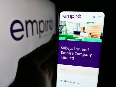Stuttgart, Almanya - 03-06-2025: Kanada şirketi Empire Company Limited 'in web sayfası olan cep telefonu logosu önünde ekranda. Telefon ekranının merkezine odaklan.
