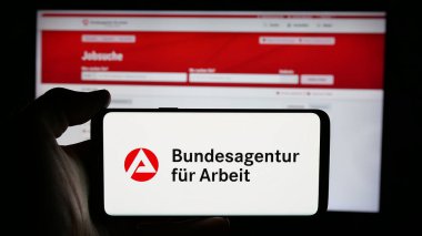Stuttgart, Almanya - 03-07-2025: Alman federal ajansı Bundesagentur fuer Arbeit 'in logosunun bulunduğu cep telefonu web sayfası önünde ekranda. Telefon ekranına odaklan.