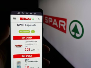 Stuttgart, Almanya - 03-07-2025: İsviçreli perakende şirketi SPAR Holding AG 'nin web sayfası ile cep telefonu tutan kişi logonun önünde ekranda. Telefon ekranının merkezine odaklan.