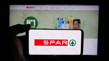Stuttgart, Almanya - 03-07-2025: İsviçreli perakende şirketi SPAR Holding AG 'nin logosuyla cep telefonu sahibi kişi iş sayfasının önünde ekranda. Telefon ekranına odaklan.