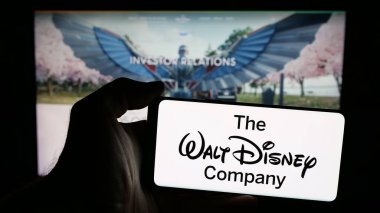 Stuttgart, Almanya - 03-07-2025: ABD eğlence sektörü logosu olan cep telefonu sahibi kişi The Walt Disney Company web sayfasının önünde ekranda. Telefon ekranına odaklan.