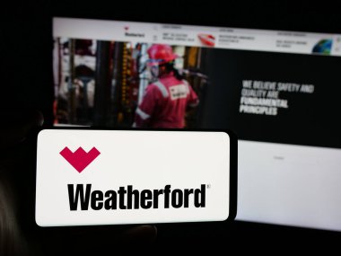Stuttgart, Almanya - 03-07-2025: ABD 'li petrol şirketi Weatherford International plc' in logosunu taşıyan akıllı telefon sahibi kişi iş sitesinin önünde ekranda. Telefon ekranına odaklan.