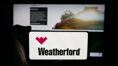 Stuttgart, Almanya - 03-07-2025: ABD 'li petrol şirketi Weatherford International plc' in logosuyla cep telefonu sahibi kişi iş sayfasının önünde ekranda. Telefon ekranına odaklan.