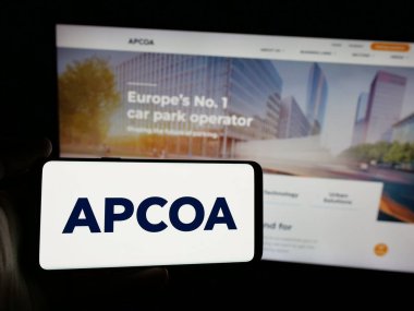 Stuttgart, Almanya - 03-04-2025: Alman firması APCOA Park AG 'nin logosunu elinde tutan kişi web sitesinin önünde ekranda. Telefon ekranına odaklan.