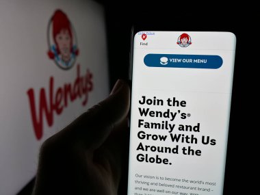 Stuttgart, Almanya - 03-07-2025: ABD 'li restoran şirketi Wendy' s International LLLC 'nin internet sayfası ile cep telefonu tutan kişi logonun önünde ekranda. Telefon ekranının merkezine odaklan.