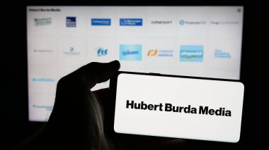 Stuttgart, Almanya - 03-07-2025: Alman Hubert Burda Media Holding KG logosunun bulunduğu cep telefonu sahibi kişi web sayfası önünde ekranda. Telefon ekranına odaklan.