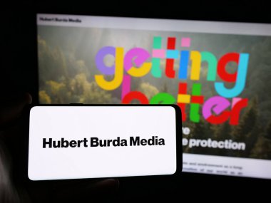 Stuttgart, Almanya - 03-07-2025: Alman Hubert Burda Media Holding KG 'nin logosunu taşıyan kişi iş sitesinin önünde ekranda. Telefon ekranına odaklan.
