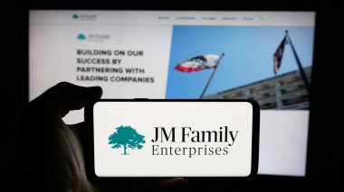 Stuttgart, Almanya - 03-09-2025: ABD 'li JM Family Enterprises Inc. (JMFE) şirketinin logosunun bulunduğu cep telefonu web sayfası önünde. Telefon ekranına odaklan.
