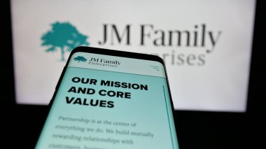 Stuttgart, Almanya - 03-09-2025: ABD 'li JM Family Enterprises Inc. (JMFE) şirketinin logosunun yer aldığı cep telefonu web sitesi önünde ekranda. Telefon ekranının sol üst kısmına odaklan.