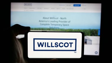 Stuttgart, Almanya - 03-09-2025: Web sayfasının önünde WillScot Mobile Mini Holding şirketinin logosunu elinde tutan kişi. Telefon ekranına odaklan.