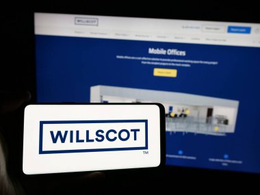 Stuttgart, Almanya - 03-09-2025: WillScot Mobile Mini Holding şirketinin logosuna sahip akıllı telefon sahibi kişi web sitesinin önünde ekranda. Telefon ekranına odaklan.