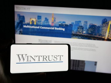 Stuttgart, Almanya - 03-09-2025: Bankacılık şirketi Wintrust Financial Corporation 'ın logosunu elinde tutan kişi web sitesinin önünde ekranda. Telefon ekranına odaklan.