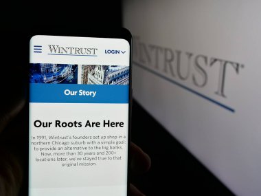 Stuttgart, Almanya - 03-09-2025: Bankacılık şirketi Wintrust Financial Corporation 'ın internet sayfası ile logo önünde cep telefonu tutan kişi. Telefon ekranının merkezine odaklan.