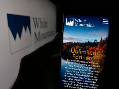 Stuttgart, Almanya - 03-09-2025: White Mountains Sigorta Grubu Ltd. şirketinin internet sayfası ile logo önünde cep telefonu tutan kişi. Telefon ekranının merkezine odaklan.