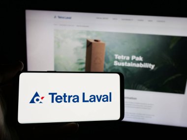 Stuttgart, Almanya - 03-10-2025: İnternet sitesi önünde ambalaj şirketi Tetra Laval Group 'un logosuna sahip akıllı telefon sahibi kişi. Telefon ekranına odaklan.