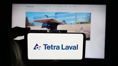 Stuttgart, Almanya - 03-10-2025: İnternet sayfası önünde ambalaj şirketi Tetra Laval Group 'un logosuyla cep telefonu tutan kişi. Telefon ekranına odaklan.