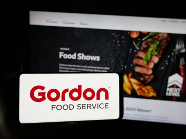 Stuttgart, Almanya - 03-10-2025: ABD 'li Gordon Food Service Inc. (GFS) şirketinin logosuna sahip akıllı telefon sahibi kişi web sitesinin önünde ekranda. Telefon ekranına odaklan.