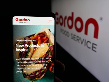 Stuttgart, Almanya - 03-10-2025: ABD 'li Gordon Food Service Inc. (GFS) şirketinin internet sayfası logonun önünde cep telefonu tutan kişi. Telefon ekranının merkezine odaklan.