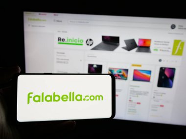 Stuttgart, Almanya - 03-10-2025: Şilili perakende şirketi Falabella S.A. 'nın logosunu elinde tutan kişi web sitesinin önünde ekranda. Telefon ekranına odaklan.