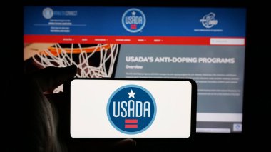 Stuttgart, Almanya - 03-12-2025: İnternet sayfası önünde ABD Anti-Doping Ajansı 'nın (USADA) logosunu elinde tutan kişi. Telefon ekranına odaklan.