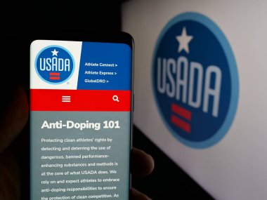 Stuttgart, Almanya - 03-12-2025: ABD Anti-Doping Ajansı 'nın (USADA) web sayfası logo önünde ekranda bulunan kişi. Telefon ekranının merkezine odaklan.