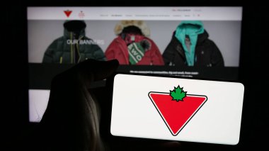 Stuttgart, Almanya - 03-13-2025: Canadian Tire Corporation Limited şirketinin logosunu elinde tutan kişi web sayfasının önünde ekranda. Telefon ekranına odaklan.