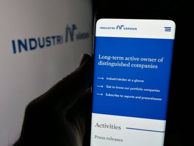Stuttgart, Almanya - 03-13-2025: İsveçli yatırım şirketi Industrivarden AB 'nin web sayfası ile logo önünde cep telefonu tutan kişi. Telefon ekranının merkezine odaklan.