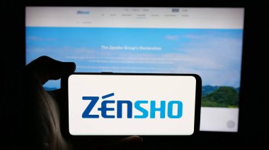 Stuttgart, Almanya - 03-13-2025: Japon restoran şirketi Zensho Co. Ltd. 'nun logosunu elinde tutan kişi web sayfasının önünde ekranda. Telefon ekranına odaklan.