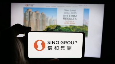 Stuttgart, Almanya - 03-14-2025: İnternet sayfası önünde Hong Kong emlak şirketi Sino Group 'un logosunu elinde tutan kişi. Telefon ekranına odaklan.