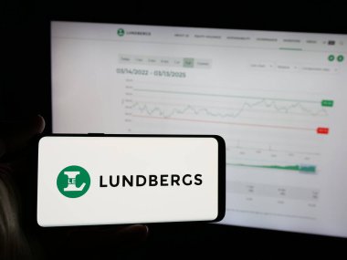 Stuttgart, Almanya - 03-14-2025: Web sitesinin önünde, üzerinde L E Lundbergforetagen AB (Lundbergs) şirketinin logosu olan akıllı telefon bulunduran kişi. Telefon ekranına odaklan.