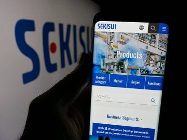Stuttgart, Almanya - 03-18-2025: Japon firması Sekisui Chemical Co. Ltd. logo önünde ekranda logosu olan kişi. Telefon ekranının merkezine odaklan.