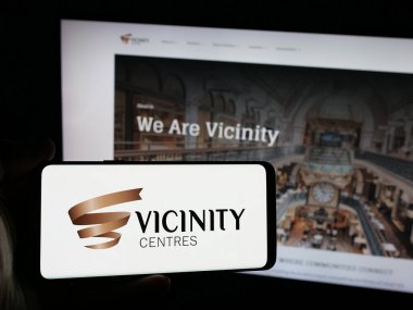 Stuttgart, Almanya - 03-18-2025: Avustralyalı emlak şirketi Vicinity Centrals 'ın logosunu elinde tutan kişi web sitesinin önünde ekranda. Telefon ekranına odaklan.