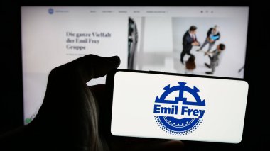 Stuttgart, Almanya - 03-18-2025: İsviçreli otomotiv şirketi Emil Frey Holding AG 'nin logosuna sahip cep telefonu sahibi kişi web sitesinin önünde ekranda. Telefon ekranına odaklan.